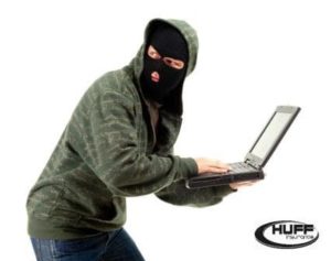 Picture of cyber criminal in a mask with a laptop for use in the identity theft blog by Huff Insurance.