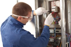 Professional electrician securing wiring in a junction box, representing Huff Insurance's comprehensive electrician insurance coverage in Pasadena, MD.