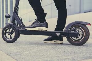 Close up image of a man on an electric scooter. 